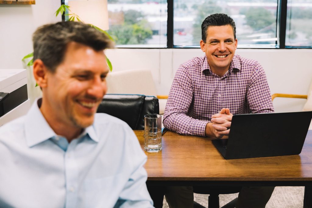 2 coworkers at Stepping Forward Technology in Colorado Springs working and smiling
